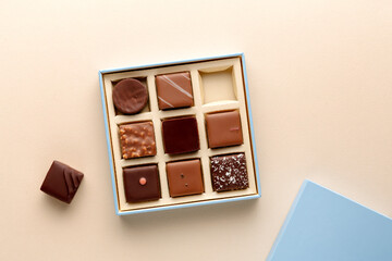Minimal flatlay of open box with chocolate squares on beige background, elegant candy dessert packaging mockup concept
