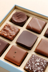 Minimal flatlay of open box with chocolate squares on beige background, elegant candy dessert packaging mockup concept
