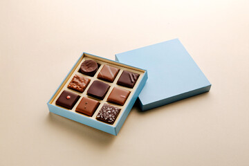 Minimal flatlay of open box with chocolate squares on beige background, elegant candy dessert packaging mockup concept