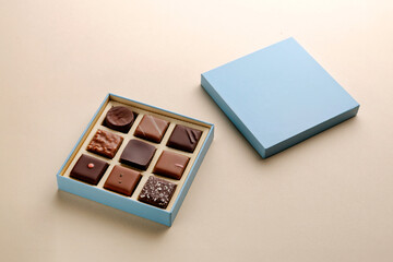 Minimal flatlay of open box with chocolate squares on beige background, elegant candy dessert packaging mockup concept