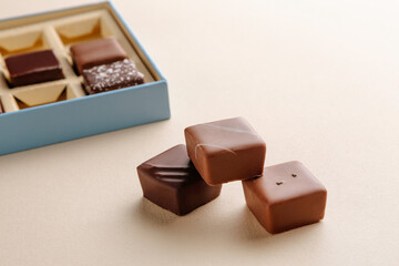 Minimal flatlay of open box with chocolate squares on beige background, elegant candy dessert packaging mockup concept