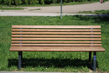 A modern wooden bench on a green lawn in a quiet city park.
