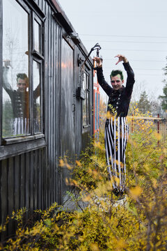 Fototapeta A Mysterious Performer Eerily Posing Outside an Old Vintage Train Car in an Urban Setting