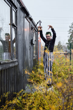 Fototapeta A mysterious performer in striped attire stands by an abandoned building, evoking curiosity