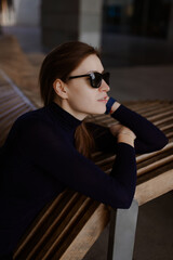 Stylish tech-savvy woman in black outfit posing in urban architecture – lifestyle shoot