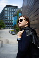 Stylish tech-savvy woman in black outfit posing in urban architecture – lifestyle shoot