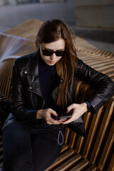 Stylish tech-savvy woman in black outfit posing in urban architecture – lifestyle shoot
