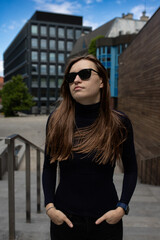 Stylish tech-savvy woman in black outfit posing in urban architecture – lifestyle shoot