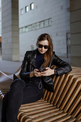 Stylish tech-savvy woman in black outfit posing in urban architecture – lifestyle shoot