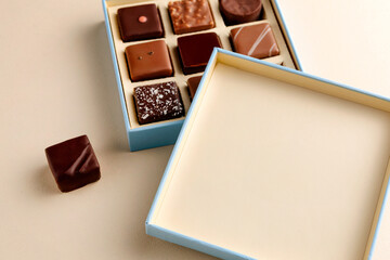 Minimal overhead shot of open box with chocolate squares on beige background, elegant candy dessert packaging mockup concept