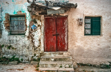 eingescanntes historisches Farbfoto der Fassade eines baufälligen Wohnhauses mit Fenster, Treppe und Eingangstür auf der griechischen Insel Korfu