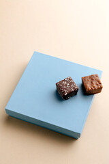 Minimal overhead shot of closed box with chocolate bonbons on beige background, elegant chocolate packaging mockup concept