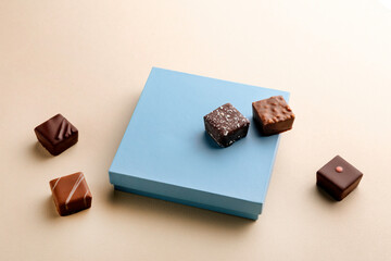 Minimal overhead shot of closed box with chocolate bonbons on beige background, elegant chocolate packaging mockup concept