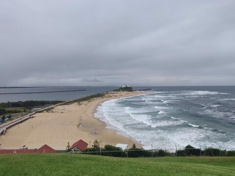 View of Nobby's Beach in Newcastle, Australia, from a grassy hill on a cloudy and stormy day