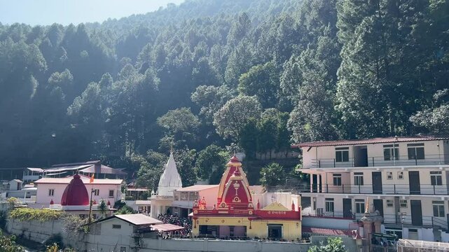 View of Kainchi Dham - Shri Neeb Karori Baba Ashram temple near a mountain forest under blue sky