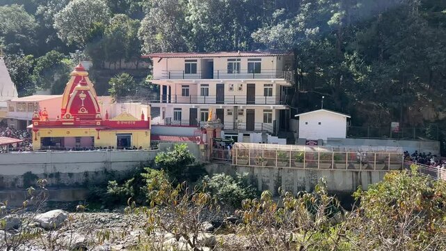 View of Kainchi Dham - Shri Neeb Karori Baba Ashram temple with visitors near a forest on sunny day