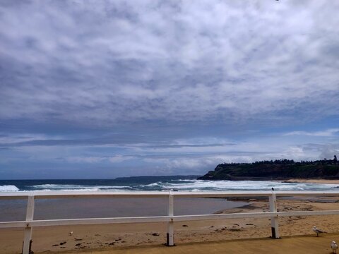 View of Newcastle Beach behind a fence on a sunny but cloudy day