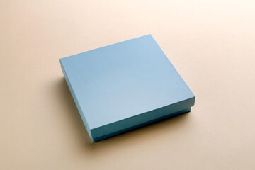 Minimal overhead shot of light blue square box on beige background, clean packaging mockup concept