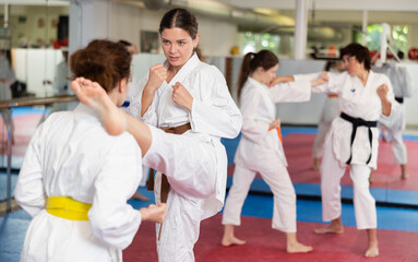 Obraz premium Sportive womens working in pair mastering new karate moves during group class