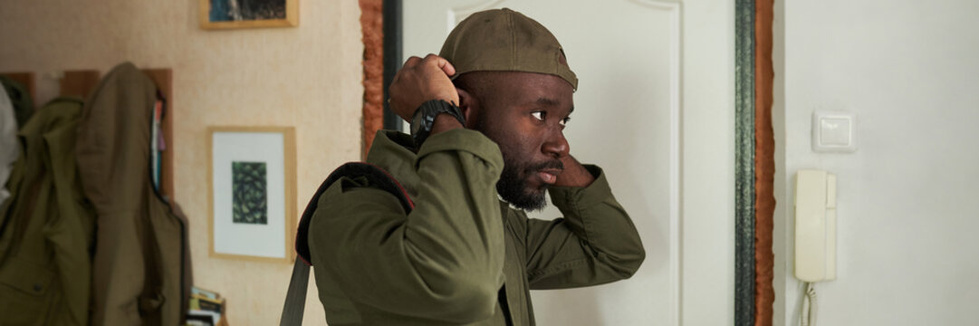 African American Man Adjusting His Cap at Home Header