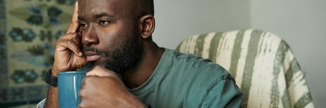 Contemplating Man Holding Mug by Patterned Wall Header