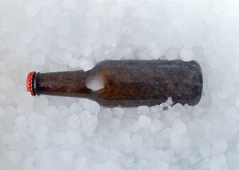 Brown beer bottle buried in a pile of ice cubes