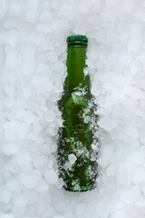 Green beer bottle buried in a pile of ice cubes