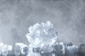 Bowl with ice cubes backlit with cold steam in background