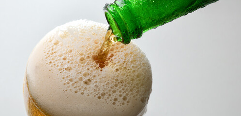 Filling glass with sparkling drink from green bottle
