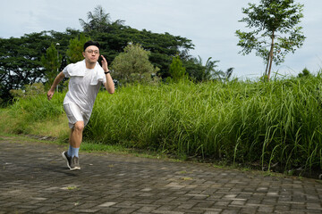 Man Running Outdoors on Stone Path Near Green Grass and Trees
