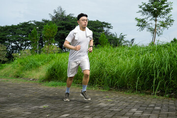 Man Running Outdoors on Stone Path Near Green Grass and Trees