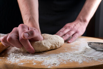 Baking concept. Man preparing dough, kneading dough on wooden table. Man cook baking bread. Close up
