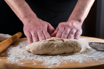 Baking concept. Man preparing dough, kneading dough on wooden table. Man cook baking bread. Close up