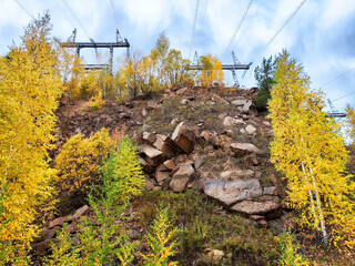 Krasnoyarsk Hydroelectric Power Station surrounded by autumn foliage and power lines in a natural landscape