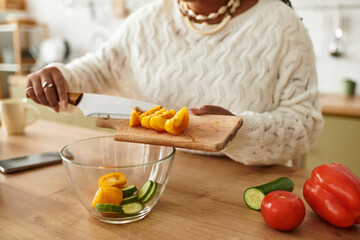 Young woman skillfully preparing a fresh salad in her cozy kitchen