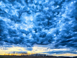 Dramatic sky filled with clouds at sunset over a quiet landscape
