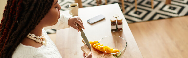 A young African American woman skillfully prepares a fresh salad in her cozy kitchen