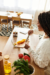 Young african american woman creates a vibrant salad in her cozy kitchen at home