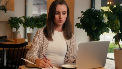 European woman girl student female studying online in cafe write information in cafeteria...