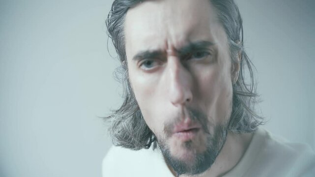 Intense Contemplation of a Young Man with Expressive Features Against a Minimalist Gray Background