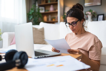 Young woman freelance worker small startup company business owner calculating tax return with data...
