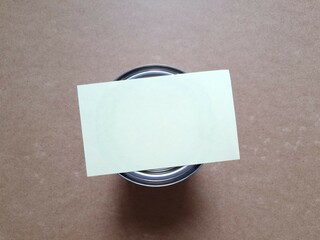 Blank sheet of yellow paper on closed tin lid of paint can