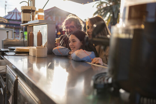 Happy family enjoying food at outdoor stall in amusement park