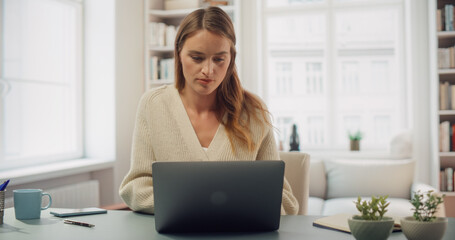 Portraiot of a Smiling Woman Working on Her Laptop. Surrounded by Bookshelves, Bright Room Digital Artist at Work. Professional Female Working in Stylish Modern Interior