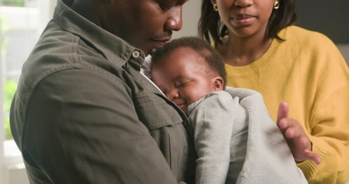 Loving Black Parents Cradle Their Sleeping Newborn Baby at Home: A Tender Moment of Family Bonding and Parental Love