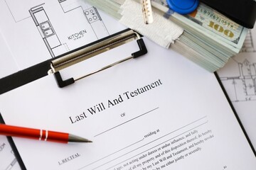 Pen and keys on Last will and testament form and planning blueprints of residential building project