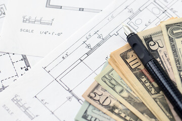 Big amount of US dollars money bills with pen and planning blueprints of residential building...