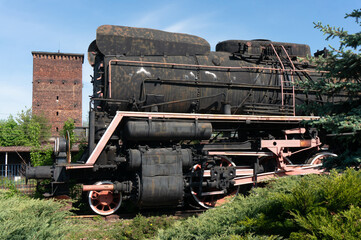 Old locomotive, tall brick tower in background, Świętokrzyskie Voivodeship. Sędziszów, Poland.