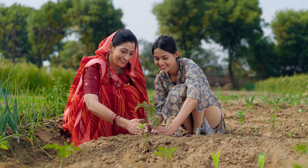Indian active mother wear saree teen age cute girl sitting help and protect to grow tree in red...