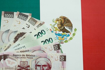 Mexican pesos money bills in big amount lies on Mexico flag close up